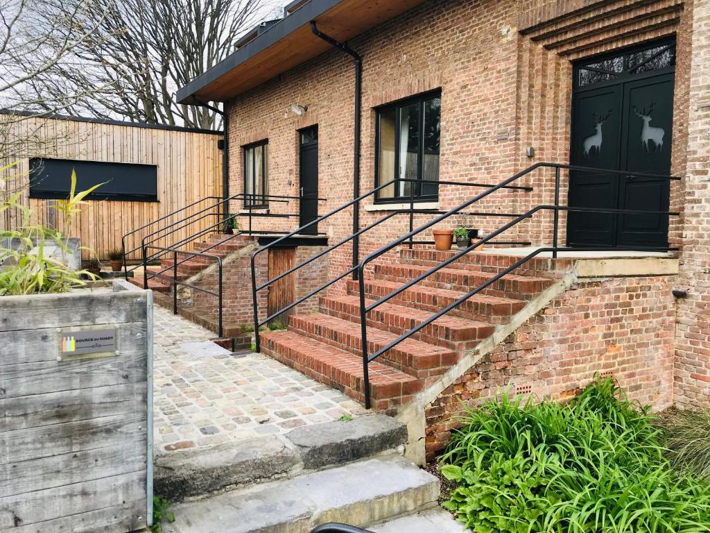 a brick building with stairs and a black door at Source du Suary in Namur