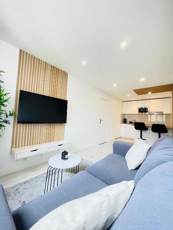 un salon avec un canapé bleu et une télévision à écran plat dans l'établissement Charmant T2, à 15 min de Paris, à Argenteuil