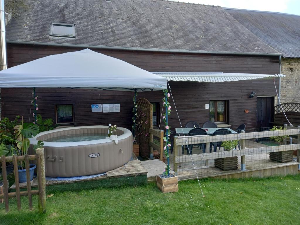 a hot tub in a yard next to a house at La Pitardière Gite in Villaines-la-Juhel