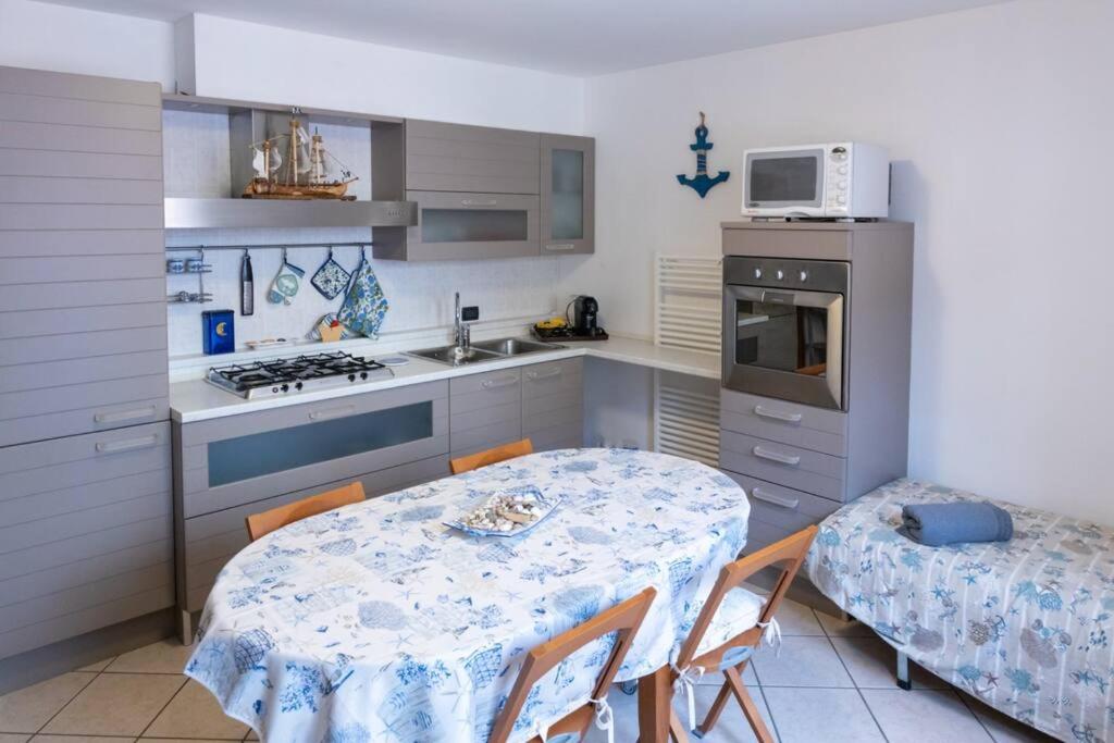eine Küche mit einem Tisch, einem Tisch und Stühlen in der Unterkunft {Il Blue di Grado} in Grado