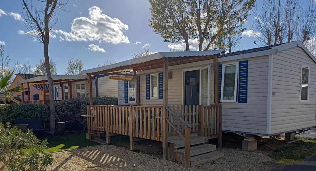 a tiny house with a porch and a deck at Mobil-home Les Locs Danous in Valras-Plage