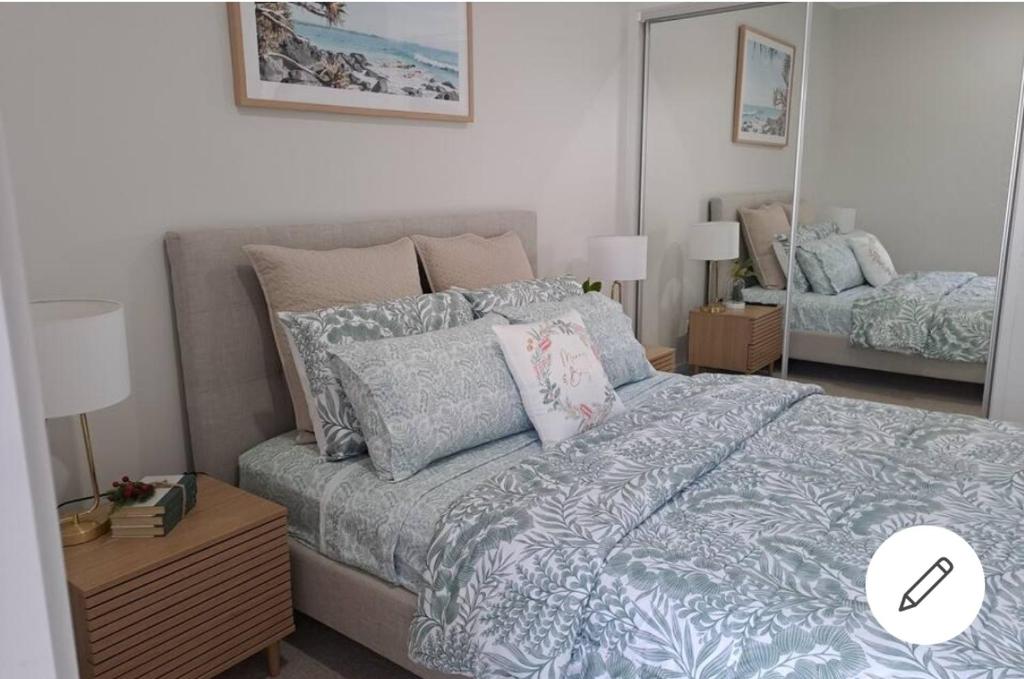um quarto com uma cama com almofadas e um espelho em Unwind in Woombye em Woombye