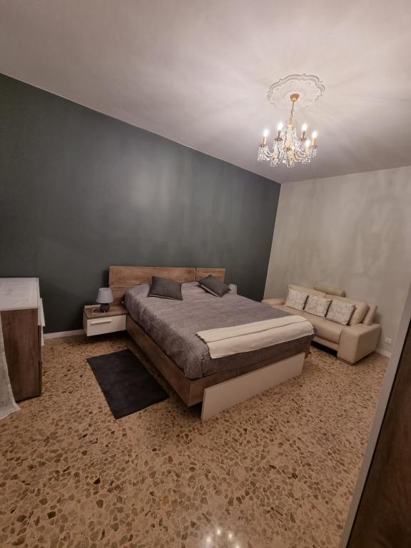 een slaapkamer met een bed, een bank en een kroonluchter bij La perle Marine in Diano Marina