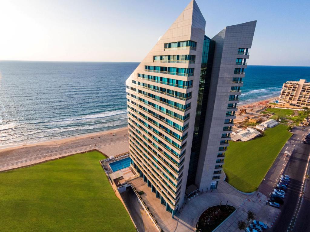 - une vue aérienne sur un grand bâtiment à côté de l'océan dans l'établissement Herbert Samuel Okeanos Suites Herzilya, à Herzliya