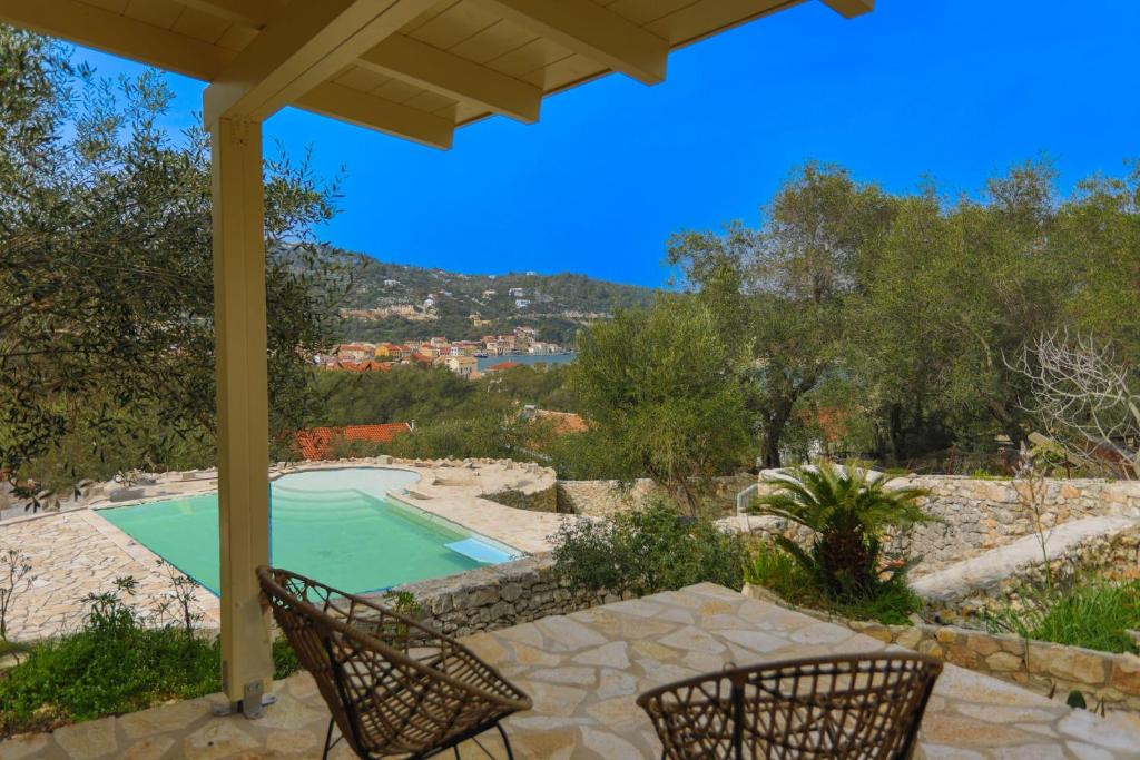 a patio with two chairs and a swimming pool at Sofi - Danilia Cottages in Gaios