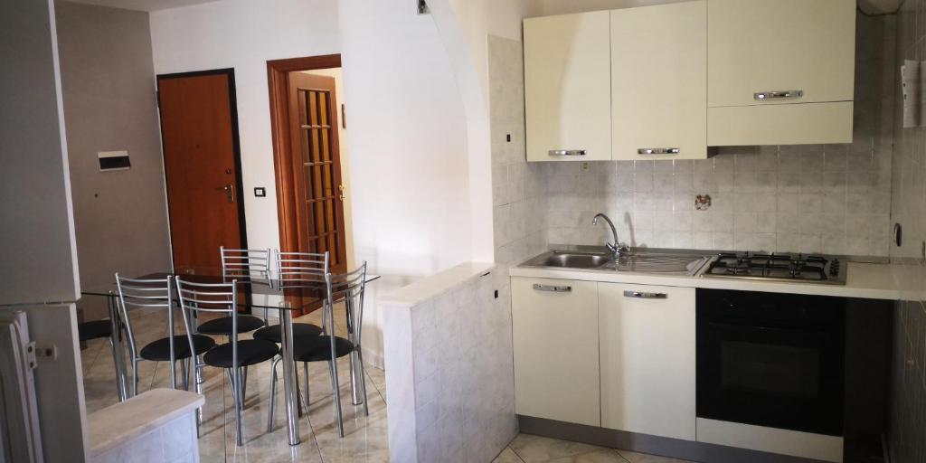 een keuken met witte kasten en een tafel en stoelen bij Appartamento del PESCATORE vista mare in Portopalo