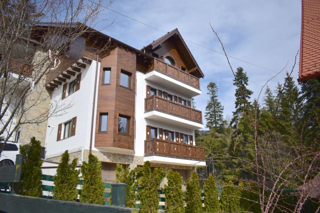 ein Haus mit Holzbalkonen und Bäumen in der Unterkunft Cosy&Minimalistic Apartments - Haret Building in Sinaia