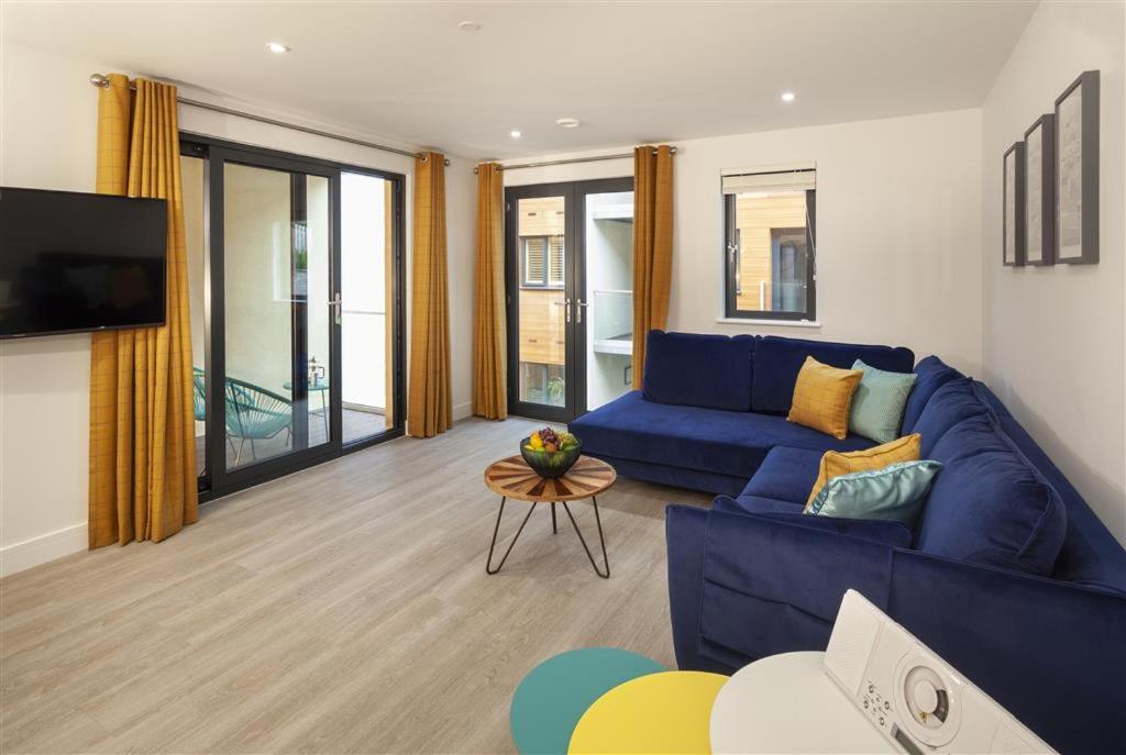 Una sala de estar con un sofá azul y un televisor. en 5 Putsborough - Luxury Apartment at Byron Woolacombe, only 4 minute walk to Woolacombe Beach!, en Woolacombe