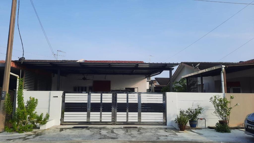 una casa con una puerta delante de una valla en BRICK HOMESTAY en Teluk Intan