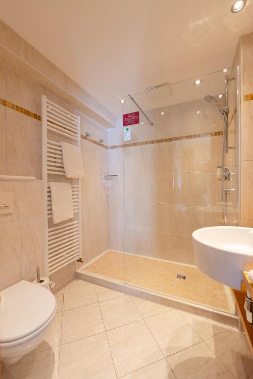 a bathroom with a shower and a toilet and a sink at Hotel Atlantic Juist in Juist
