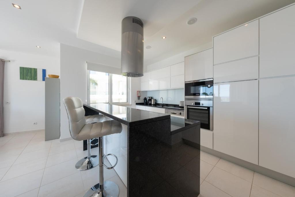 a kitchen with white cabinets and a black counter top at Porto de Mós 72 by Destination Algarve in Porto de Mós