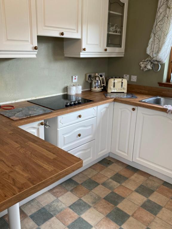 a kitchen with white cabinets and a sink at Brackenbrae Holiday Cottage in Acharacle