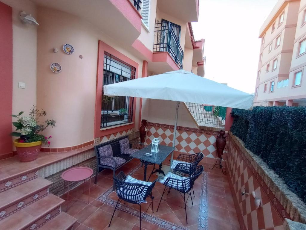 een patio met een tafel en stoelen en een parasol bij La casa del 7 in Islantilla