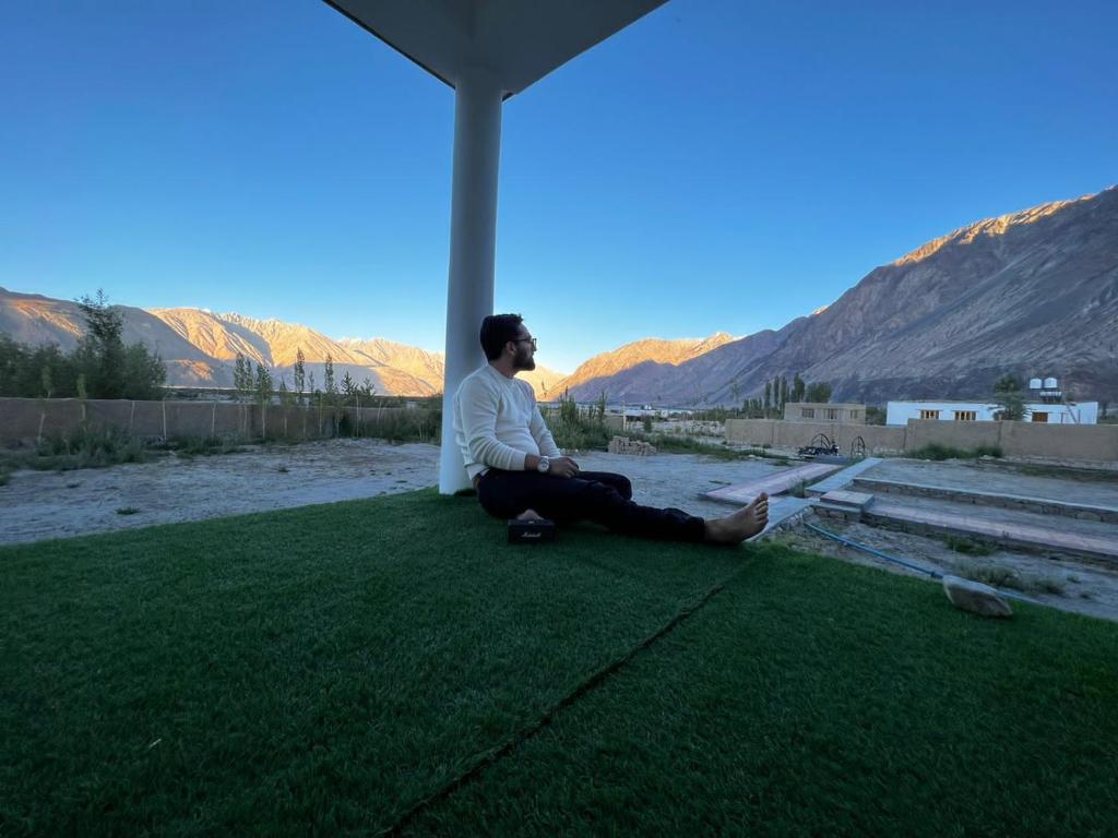 a man sitting on the grass under a tent at Natures View Residency in Hundar