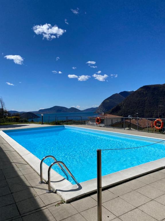 una grande piscina blu con montagne sullo sfondo di Lake view 18 a Sale Marasino