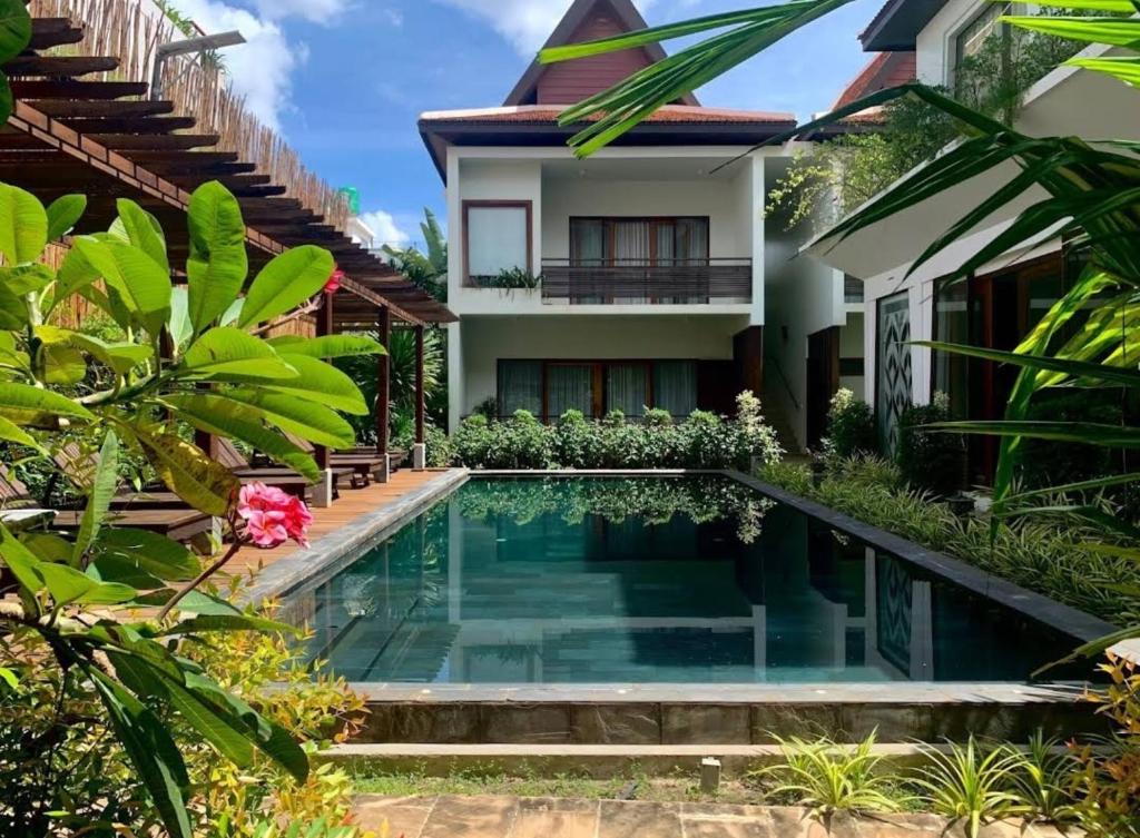a villa with a swimming pool in front of a house at Siemreap Vasinh Residence in Siem Reap
