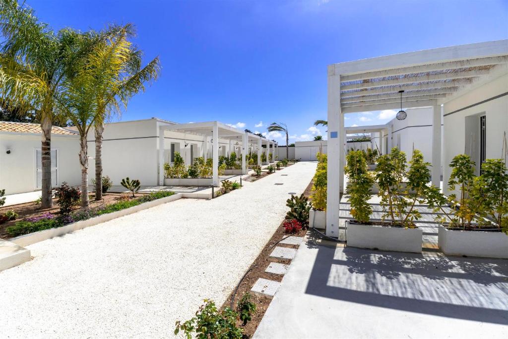 a white building with palm trees and a driveway at Amurusu Residence in Punta Secca