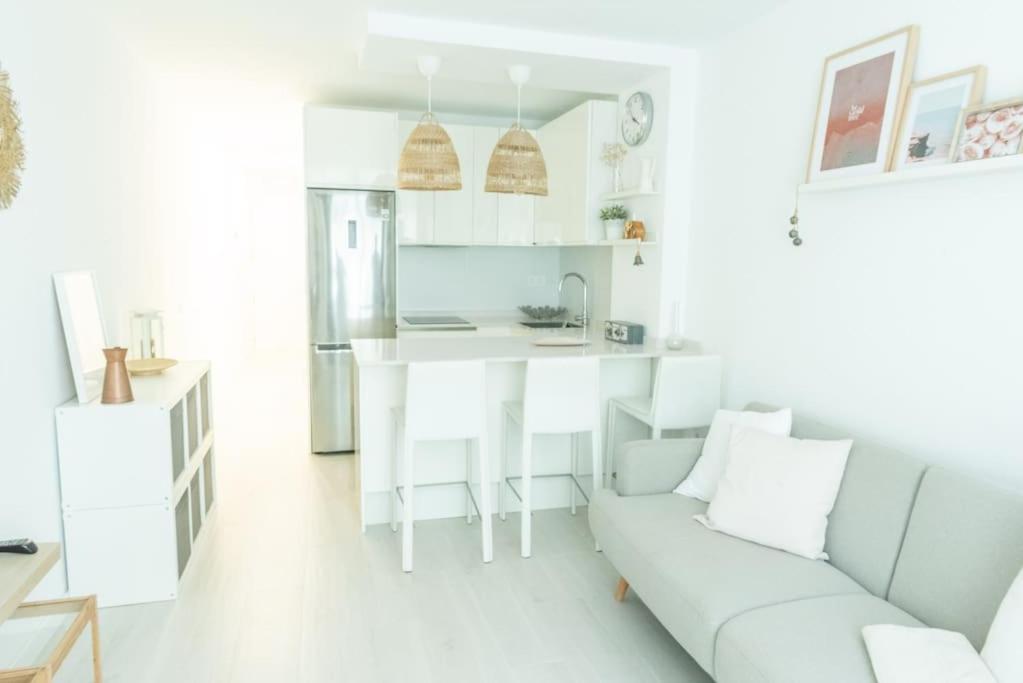 a white living room with a couch and a kitchen at Lindamar Canteras Beach House in Las Palmas de Gran Canaria