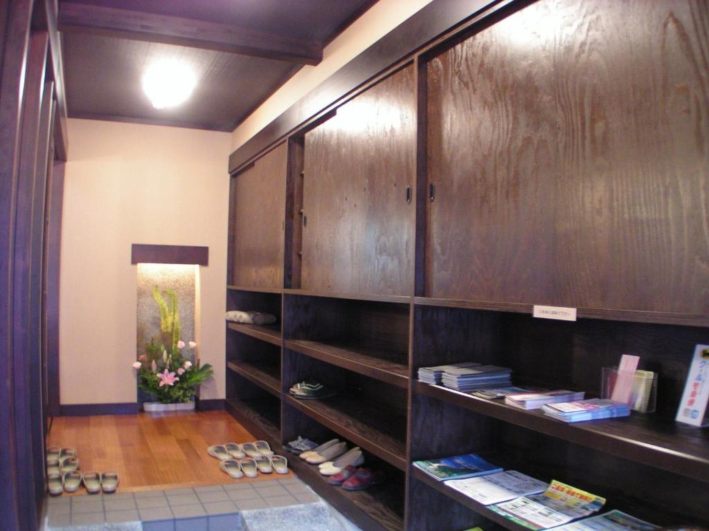 a room with wooden cabinets with shoes and books at Henmi Ryokan in Hakodate