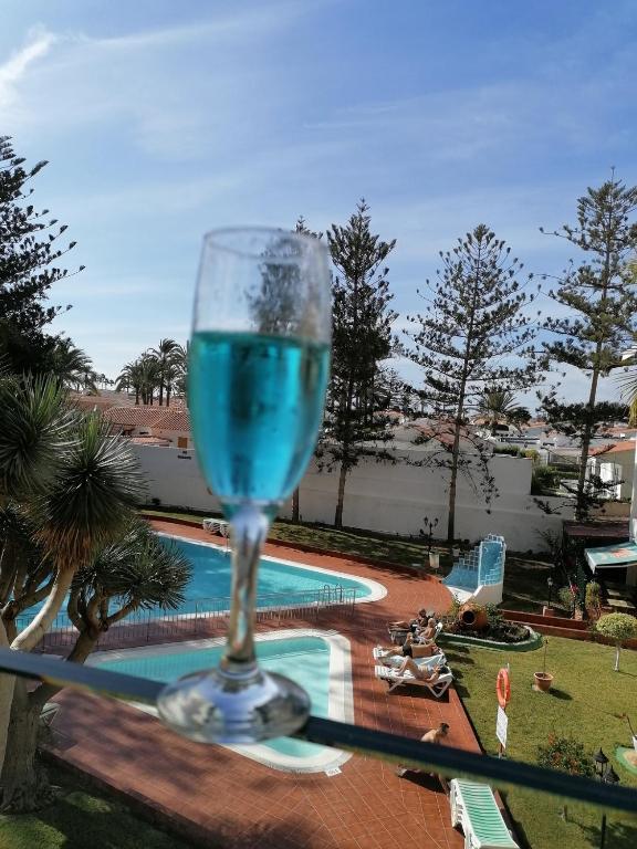 a glass of blue wine sitting on a table next to a swimming pool at Mama Yumbo in Playa del Ingles