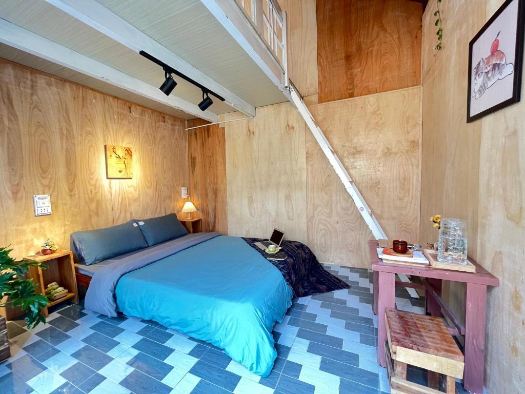 a bedroom with a blue bed and wooden walls at The Burrow Dalat in Da Thanh