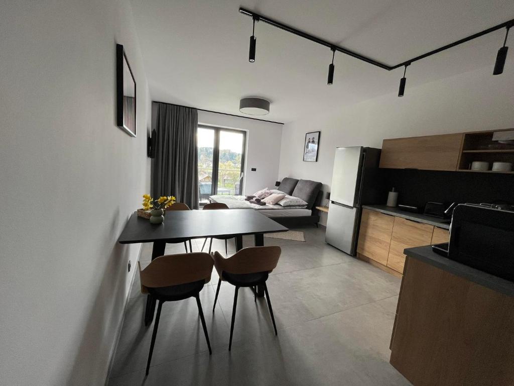 Il comprend une cuisine et un salon avec une table et des chaises. dans l'établissement Apartament w Dolinie Sanu, à Lesko