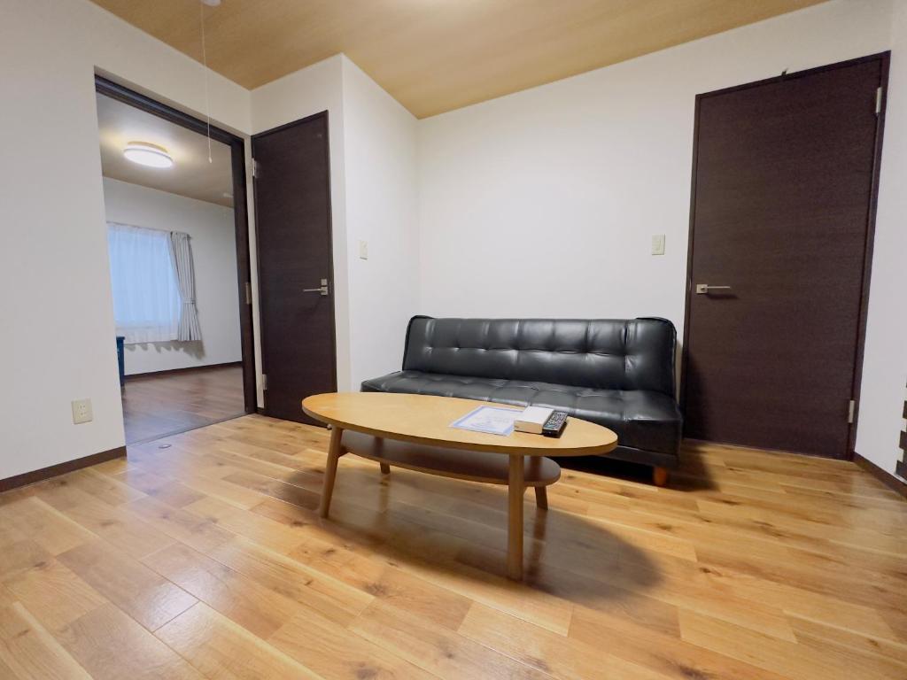 sala de estar con sofá de cuero negro y mesa en リノベーション済み室内新築　Service Apartment Sapporoザ・ハウス4LDK86㎡ en Sapporo