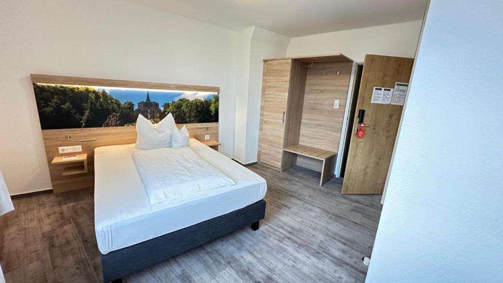 a bedroom with a white bed and a large window at Stadthotel Kassel in Kassel