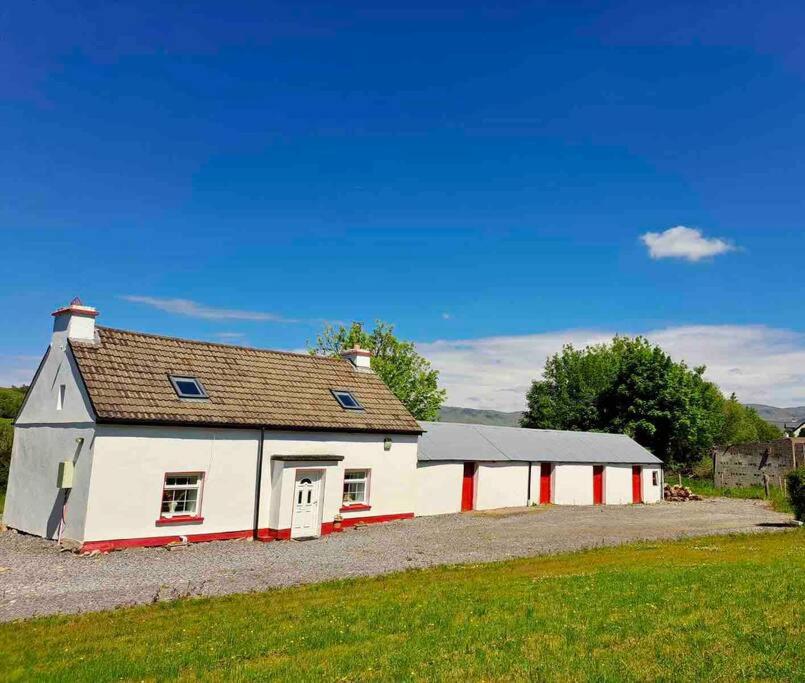 ein weißes und rotes Gebäude auf einem Feld in der Unterkunft Eanymore Farm Cottage in Donegal