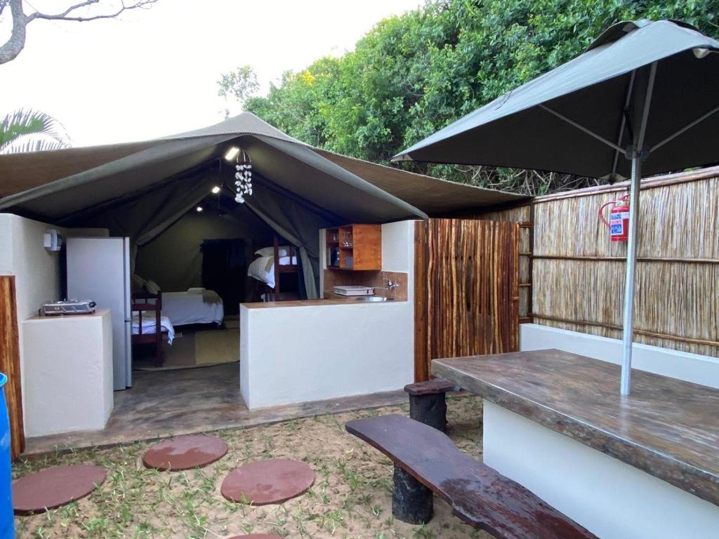 une terrasse avec une table et un parasol dans l'établissement MOZBEVOK Coconut View Resort, à Ponta do Ouro