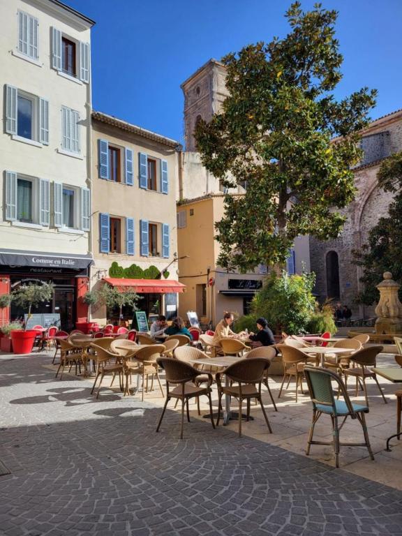 um pátio exterior com mesas, cadeiras e edifícios em Chez Mélanie et Rodolphe em La Ciotat