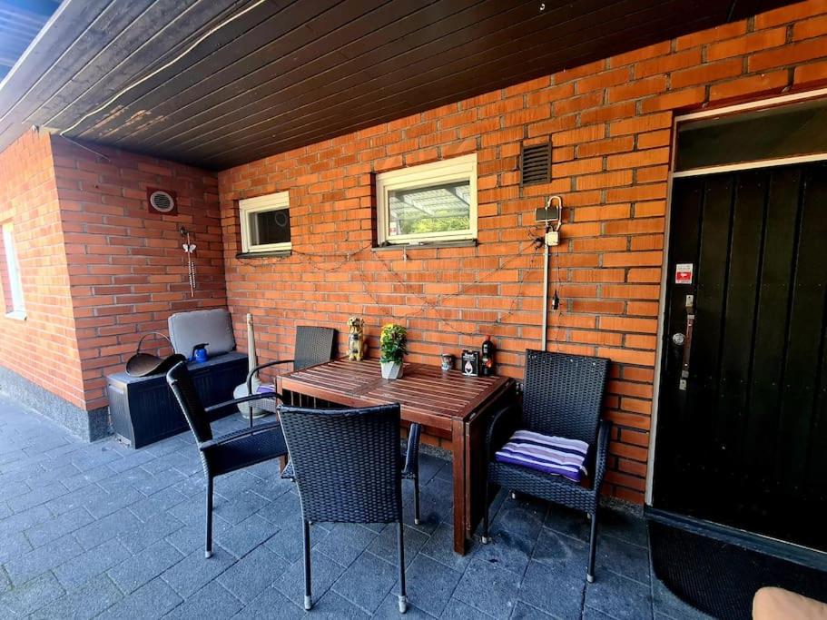 a patio with a wooden table and chairs and a brick wall at Vintage house for rent in Klaukkala