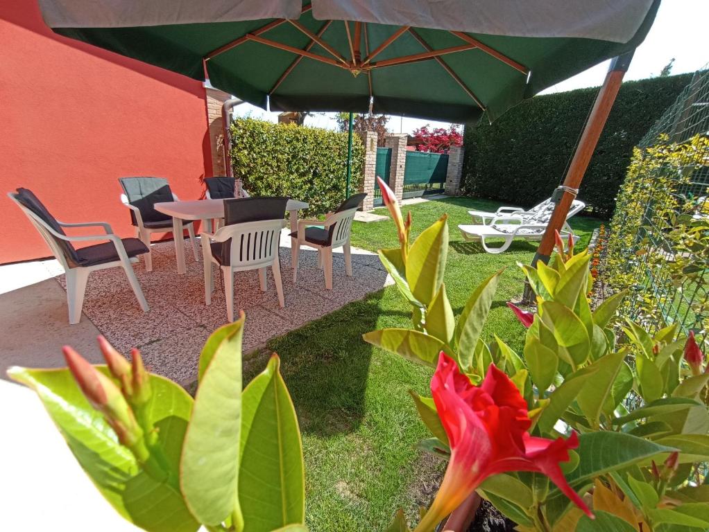 um pátio com uma mesa, cadeiras e um guarda-sol em Costalaguna Briccola con 3 camere da letto em Cavallino-Treporti