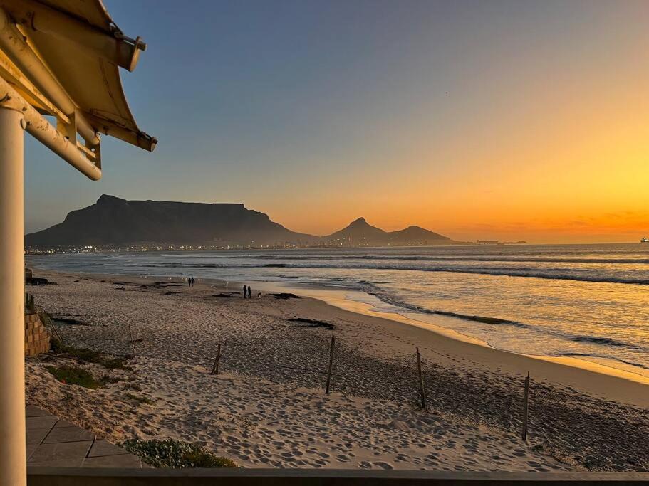 a beach at sunset with a mountain in the background at Large villa, walk to the beach in Cape Town
