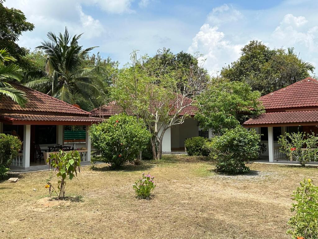 a garden in front of a house with trees at Samui Garden Resort in Bang Rak Beach