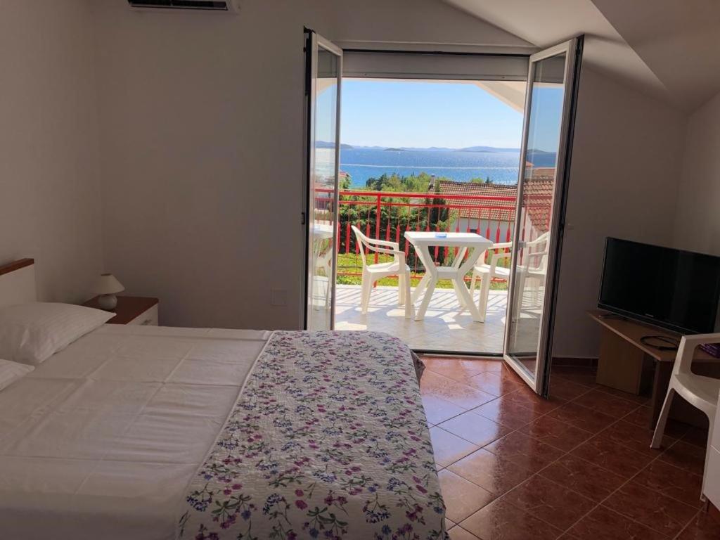 a bedroom with a bed and a balcony with a view at Francis Appartements in Pakoštane