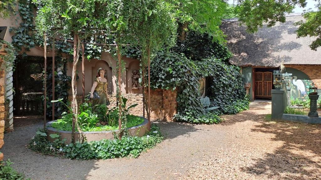 a woman is standing in front of a house with trees at Duck and Dine in Pretoria