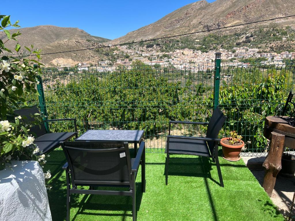a table and chairs on a lawn with a view at Cortijo Mazarrón in Güéjar-Sierra