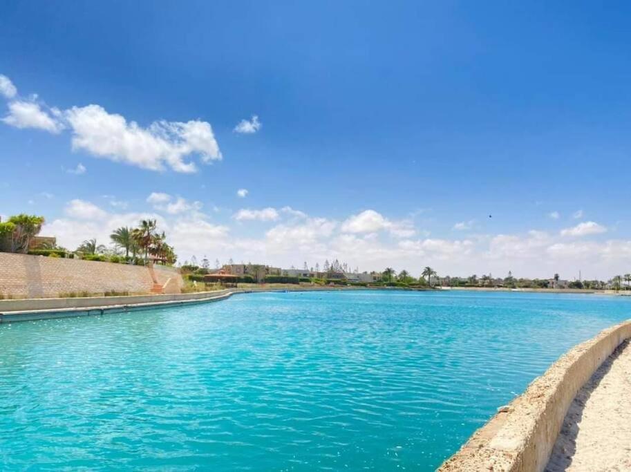 a large pool of blue water on a sunny day at فيلا مارينا٥ على البحيره ٥ غرف in El Alamein