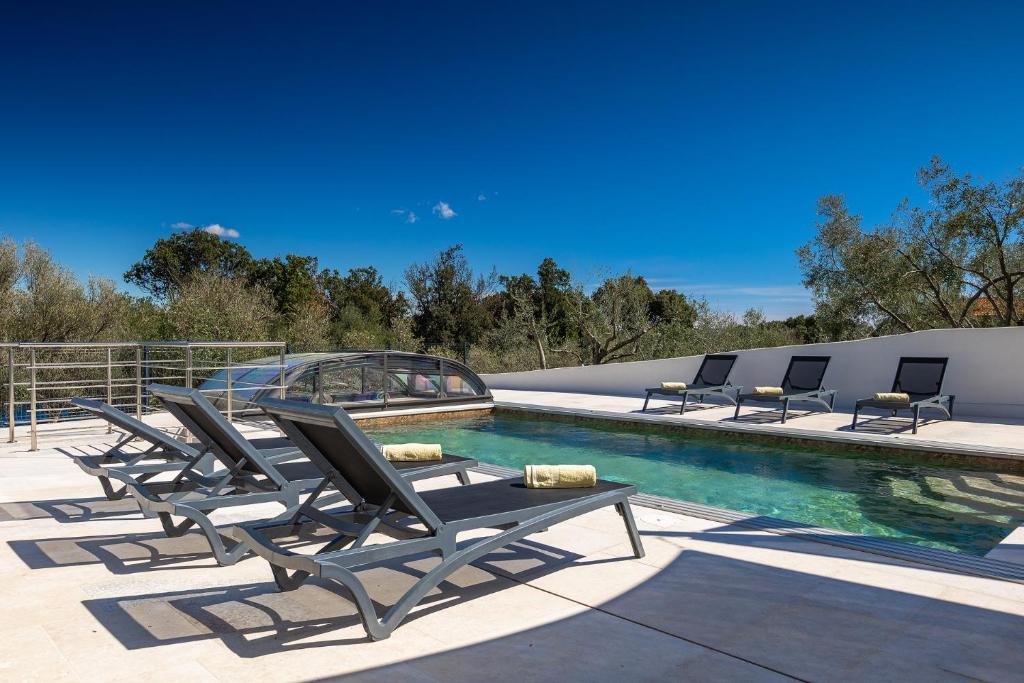 Un grupo de tumbonas junto a una piscina. en Luxusvilla in Kroatien mit Pool und Meerblick, en Ravni
