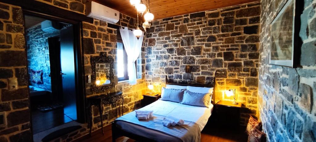 a bedroom with a bed in a brick wall at FILEMA HOME (stone house) in Anópolis