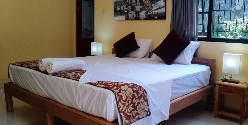 1 dormitorio con 1 cama grande con sábanas y almohadas blancas en Rindu Homestay en Undisan