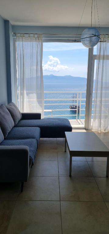 a living room with a couch and a large window at Summer Breeze Apartment Saranda in Sarandë