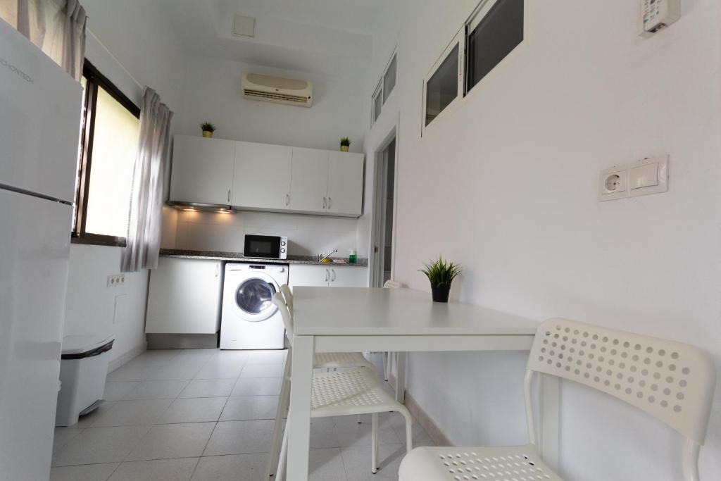 a white kitchen with a table and a washing machine at Piso Reformado in Vecindario