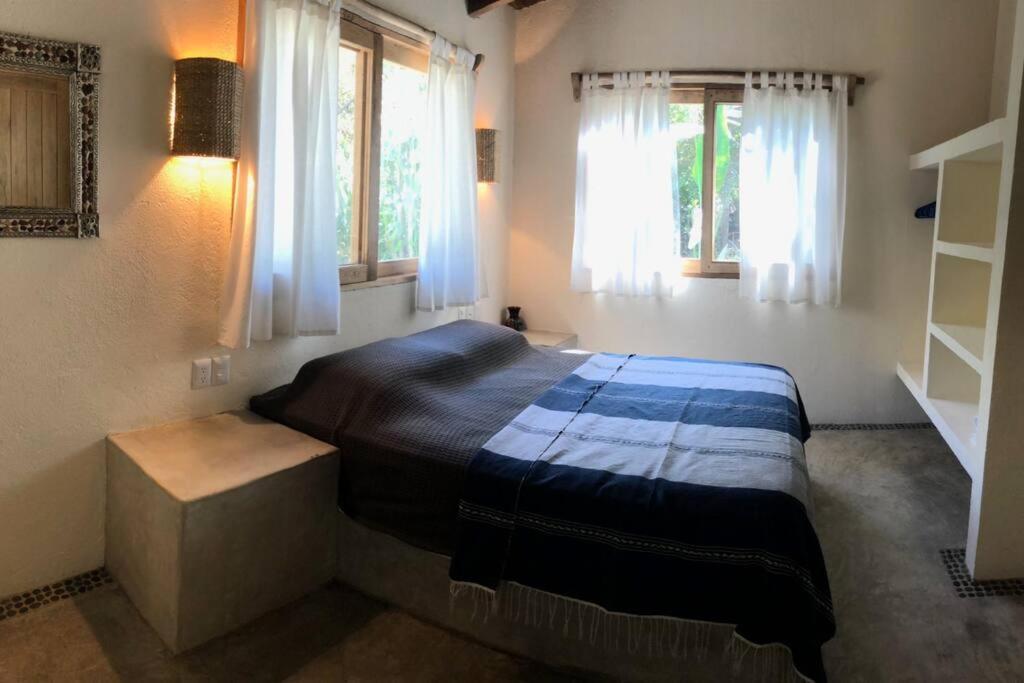 - une chambre avec un lit dans une pièce dotée de fenêtres dans l'établissement Casa Chilli entire private house with pool, à Troncones