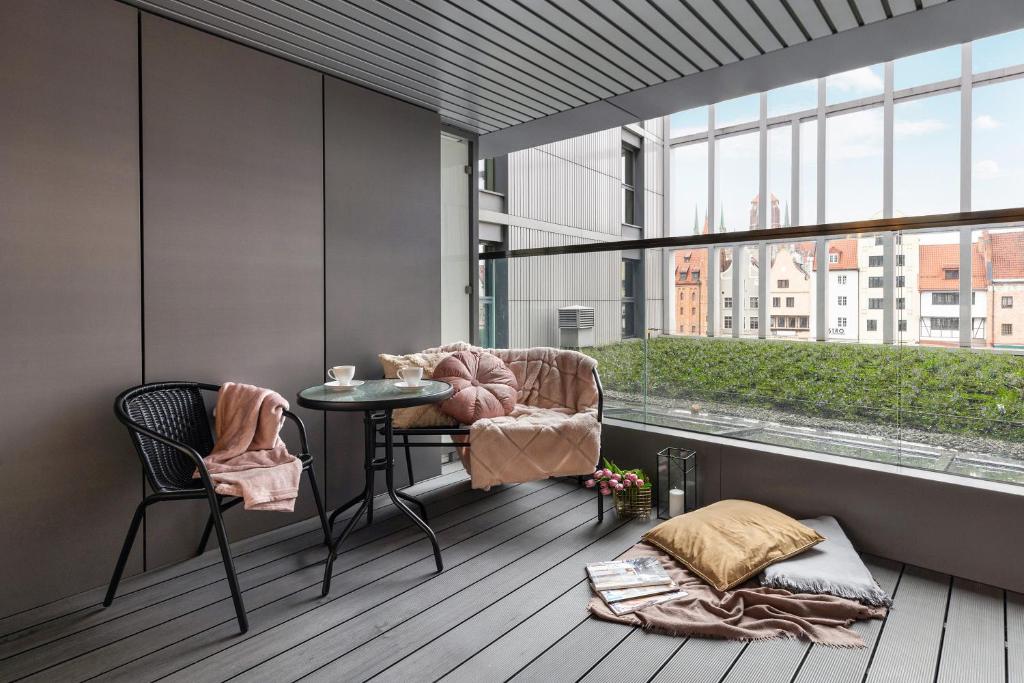 balcón con mesa, sillas y ventana en Granaria by Welcome Apartment, en Gdansk