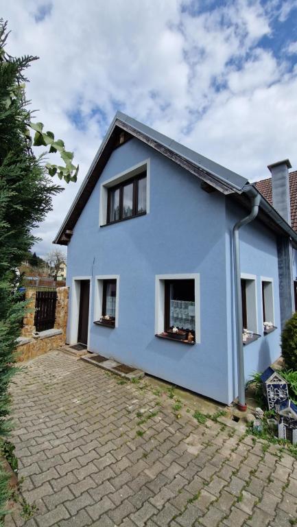 ein blaues Haus mit Fenstern auf einer Backsteineinfahrt in der Unterkunft Samostatný domeček in Klášterec nad Ohří
