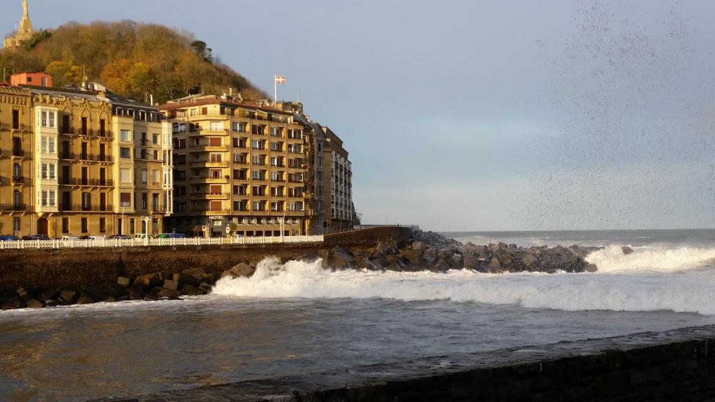 a group of buildings next to the ocean with waves at Hotel Parma in San Sebastián