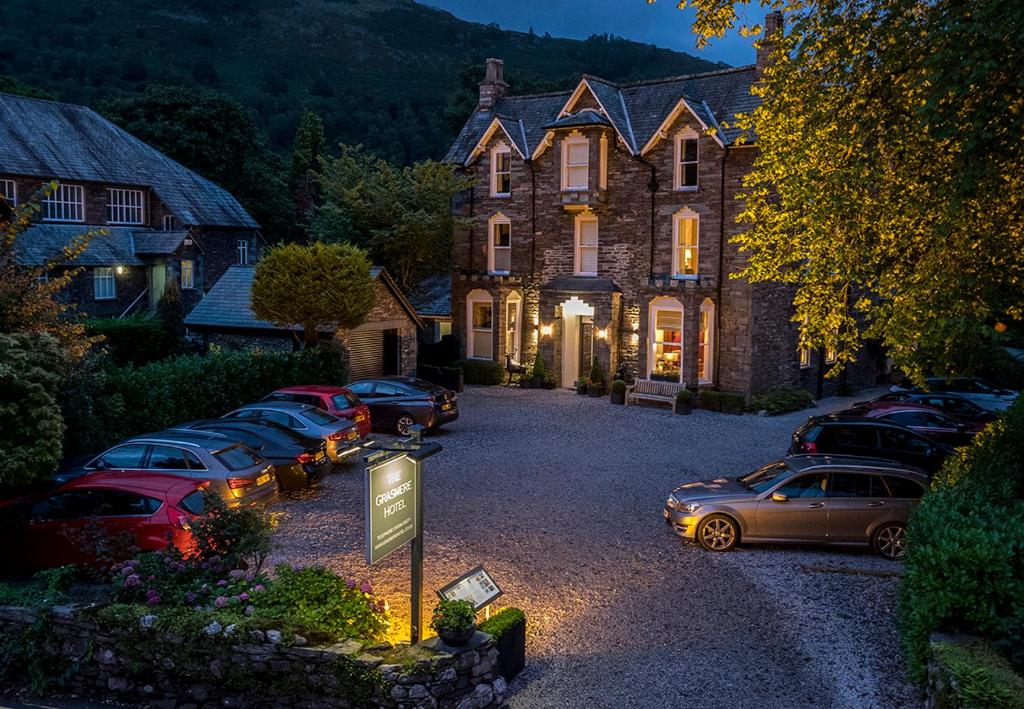 un grupo de autos estacionados frente a una casa en The Grasmere Hotel en Grasmere