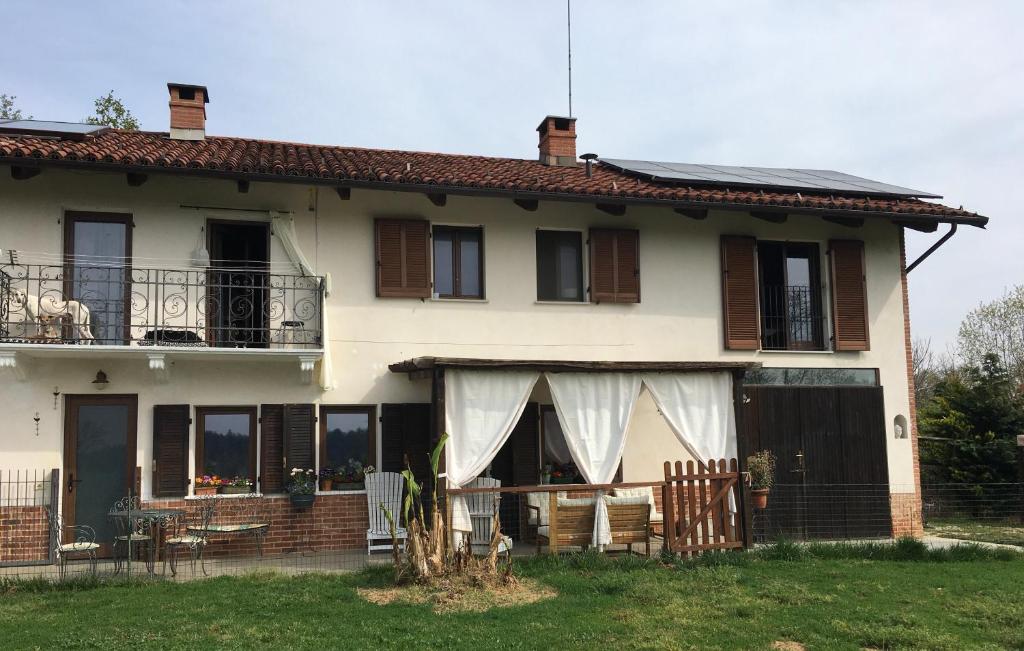 una grande casa bianca con portico e balcone di B&B Cascina Dei Levrieri a Capriglio